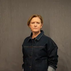 Dame med lyst hår poserer for et portrett mens hun ser inn i kamera