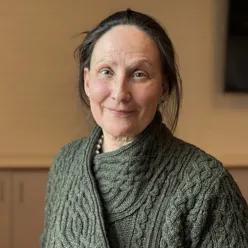 En voksen dame med langt hår som smiler til kameraet