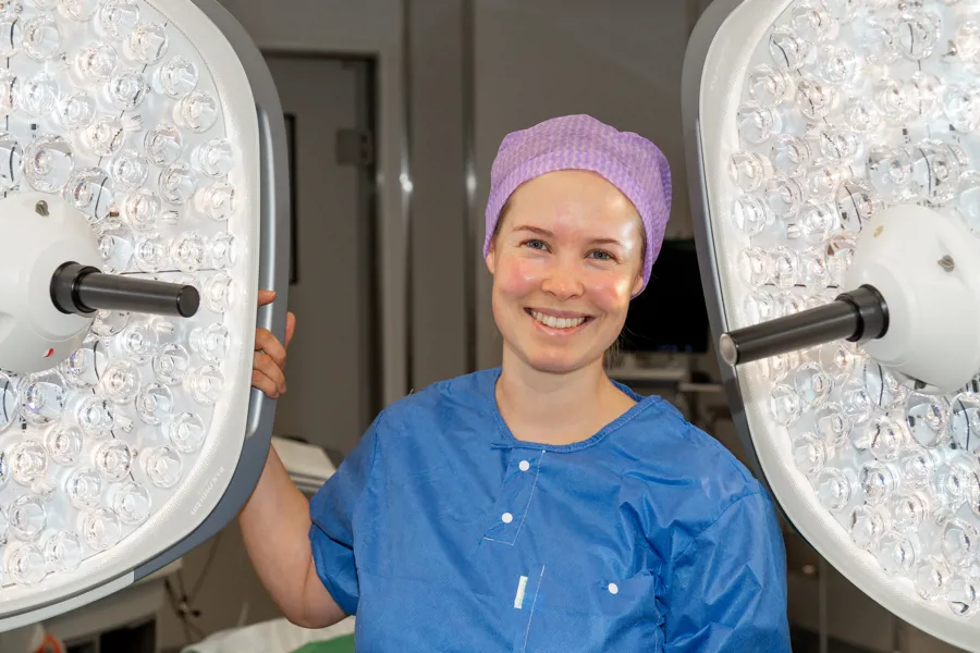 Dame holder i ei stor lampe i operasjonssalen.