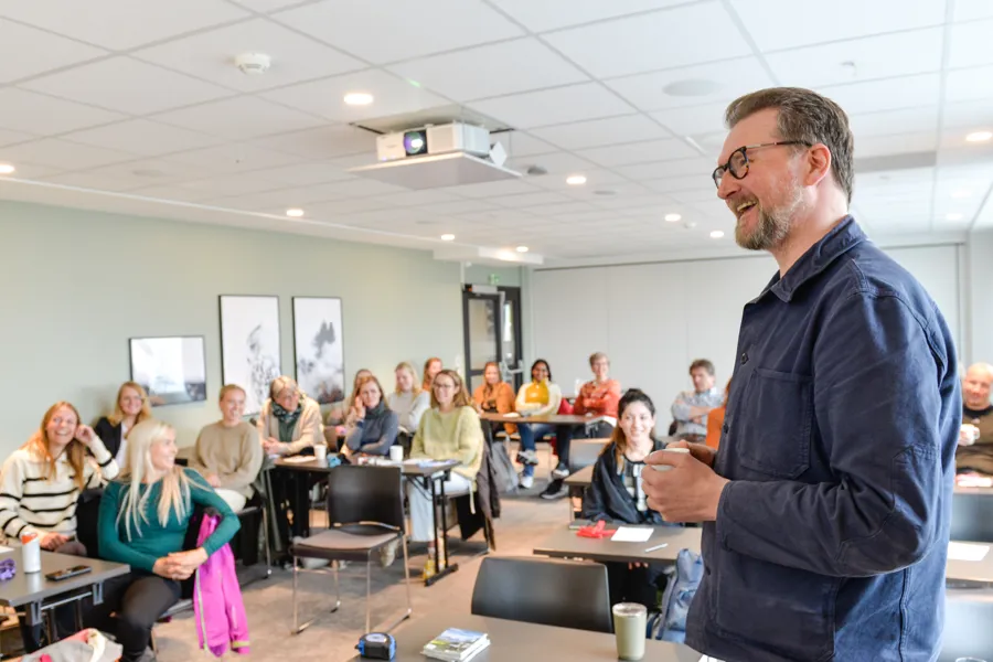 Smilende mann står foran ei forsamling